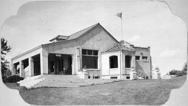 View of the club house at the Willis Case Municipal Golf Course (formerly Rocky Mountain Golf Course). The building has a tile roof and covered porch. A sign on the building reads: "Buy Tickets Inside".