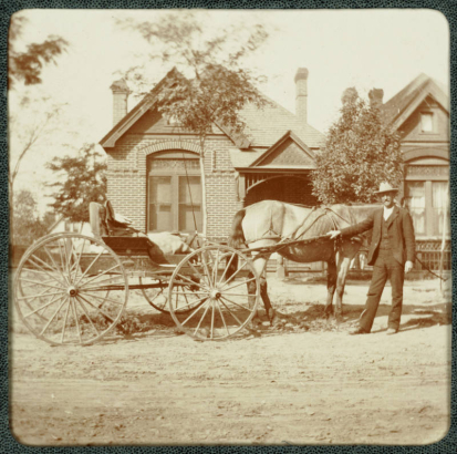A man poses by a horse-drawn buggy in front of his house in Denver, Colorado.