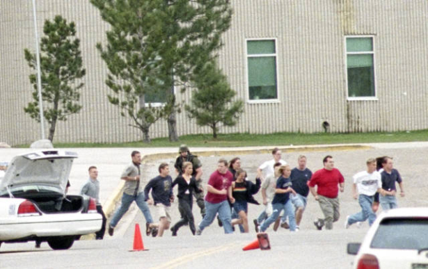 Students sprint across a parking lot toward school buses waiting to evacuate them.