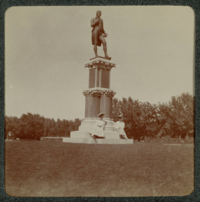 Women pose on the base of a statue of Robert Burns in City Park, Denver, Colorado.
