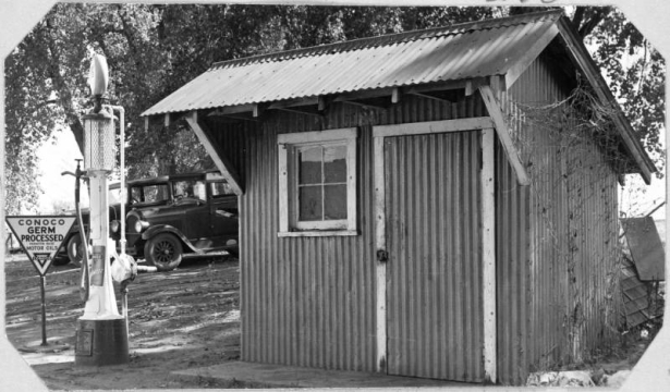 View of the gas station and pump at the Wellshire Golf Course (Wellshire Country Club) in Denver, Colorado. Automobiles are parked nearby. A sign near the pump reads: "Conoco Germ Processed Parafin Base Motor Oils".