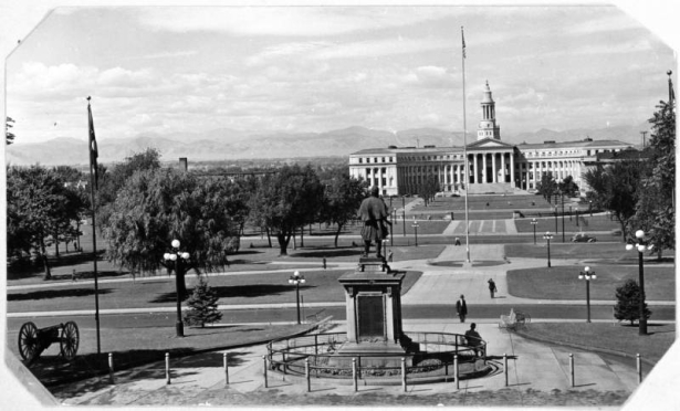 A view of Civic Center Park in Denver, Colorado from the State Capitol Building. Shows the Civil War Memorial from behind, the City and County Building, landscaping, and a canon.