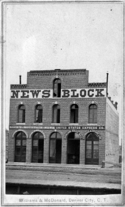 View of the Rocky Mountain News building, at 1555-59 Larimer Street, in Denver, Colorado, a brick office with arched windows and signs: "News Block," "Rocky Mountain News," "United States Express Co.," and "Overland Daily Mail Express & Stable Line.