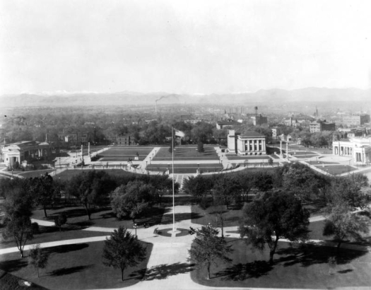 View of Civic Center in Denver, Colorado. The Greek Theater and Colonnade of Civic Benefactors and the Voorhies Memorial are on either side of the grassy area bisected by walkways. The Denver Public Library is in the park.