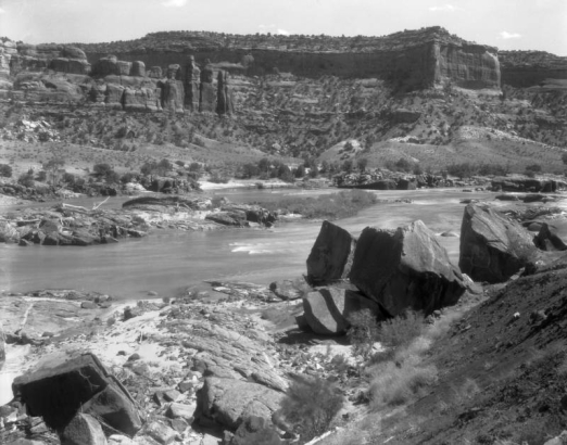 Sandstone cliffs of Ruby Canyon, in Utah or Colorado, edge the Colorado River. Pinnacles comprise the "Three Sisters" formation.