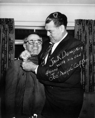Jack Dempsey poses with Joe "Awful" Coffee probably in Colorado. Both men wear suits.
