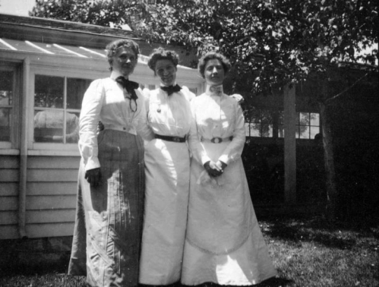Three unidentified women pose in the yard of a Denver, Colorado residence.