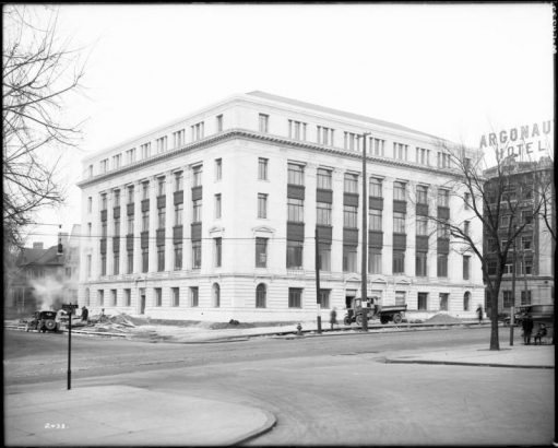 Exterior of the State Office Building, corner of Sherman Street  and Colfax Avenue, 201 East Colfax Avenue, Denver, Colorado, a five-story granite Neoclassical style structure; shows a Seerie and Varnum Contractors pickup truck and concrete sidewalk construction; Argonaut Hotel shows next door.