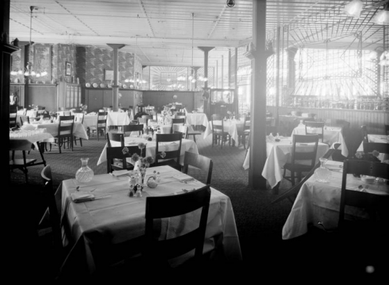 Interior view of the Daniels and Fisher store in Denver, Colorado; shows the dining room, tables with silverware and carafes, and wooden screens.