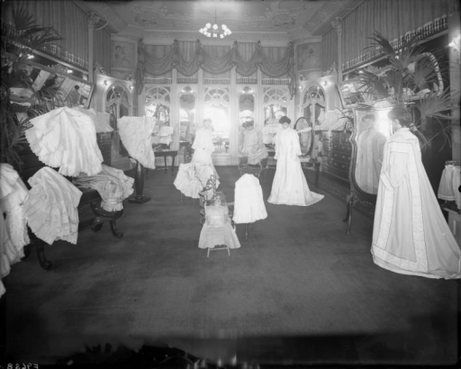 Interior view of the Daniels and Fisher store in Denver, Colorado; shows the "French Room," mannequins in lace and brocade gowns, mirrors and a doll.