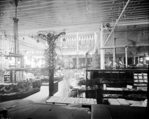 Interior view of the Daniels and Fisher store in Denver, Colorado; shows displays of clothes, plants, flowers, lamps, and the mezzanine.