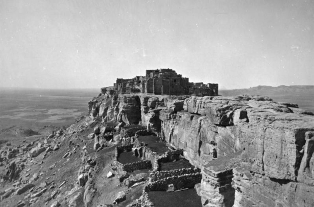 View of Walpi Pueblo, First Mesa, Arizona, shows: adobe and masonry dwellings overlooking a wide valley; stone corrals at the base of the steep rock walls.