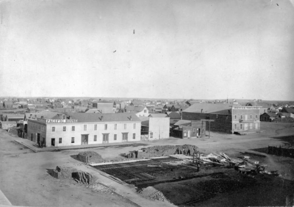 Rooftop view of 16th (Sixteenth) Street, Larimer Street and Lawrence Street in downtown Denver, Colorado. Signs on buildings read: "Pacific House" and "Denver Theatre." Shows a building construction site.