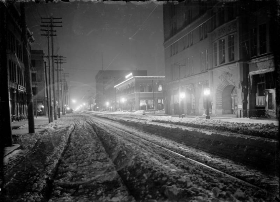 Night view of 17th (Seventeenth) Street in Denver, Colorado, at night; shows the Brown Palace Hotel, the Gas and Electric Building, and snow.