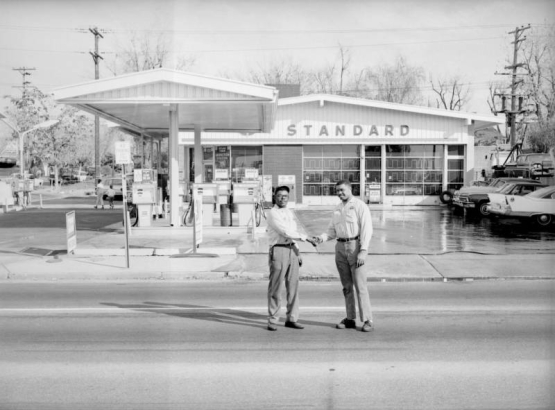 Two African American (Black) men shake hands in front of a Standard gas station at 29th and Colorado Boulevard in the Five Points neighborhood of Denver, Colorado.