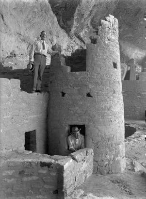 Interior view of Native American (Anasazi) Cliff Palace, at Mesa Verde National Park, Colorado; shows men in ties and hats posing by ruins of a round tower.