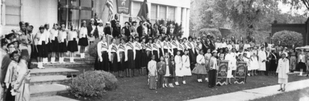 African-American men, women, and children, members of the American Woodmen's Association and Shriners, many in costume or uniform, pose with banners and pennants near the Association's office at 2100 Downing Street in the Five Points neighborhood of Denver, Colorado.