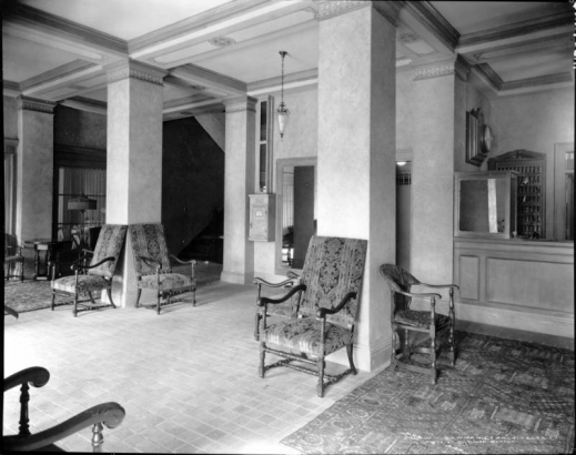 Interior view of the Colburn Hotel in Denver, Colorado; shows a  lobby with highback chairs, Oriental rugs, tile floor, mailbox, square columns and coffered ceiling.