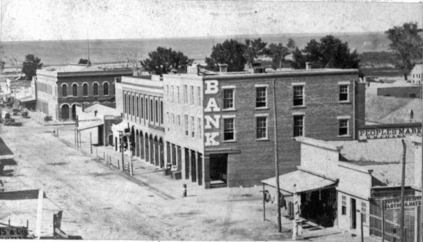 View of 15th (Fifteenth) Street in Denver, Colorado; shows businesses identified as: "Warren Hussey & Co. Bank - nw corner of Holladay & F (15th st.); First Nat. Bank nw cor F & Blake." Sign reads: "People's Market."