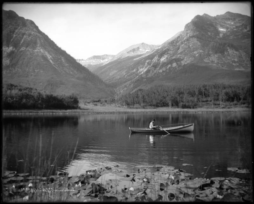 Partial view of Lily Lake near Marble, Colorado; shows lily pads and man fishing from row boat.