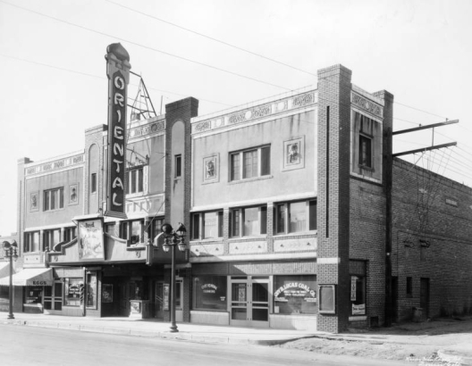 View of the Berkeley Oriental Theater at 44th (Forty-fourth) Avenue and Tennyson Street in the Berkeley neighborhood of Denver, Colorado. The three-story building has decorative trim and an electric sign that reads: "Oriental." Signs and lettering read: "Eggs," "Quality Market," "Oriental Barber Shop & Beauty Parlor," "William Boyd The Flying Fool," "Dr. S. C. Lutz "Dentist," and "Guy D. Lucas Coal Co. Direct from the Mines Sack Coal & Wood."