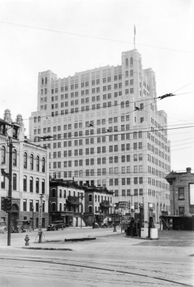 View of the Mountain States Telephone Company Building at 14th (Fourteenth) and Curtis Streets in downtown Denver, Colorado. Other buildings and a gas station are nearby. Signs read: "Cars Greased 75 [cents]," "Auto Park," and "Vandermoer-Taylor Reliable Used Cars."