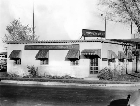 View of a business on Brighton Boulevard in Denver, Colorado; signs read: "Brannan Sand & Gravel Co. Lightning Service," "Brighton Blvd." Awnings (by Daniel Manufacturing Company) cover windows.