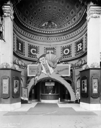 View of the Victory Theater in Denver, Colorado; shows the arched entry, ornate plaster work, and the ticket window. Display depicts a cowboy with pistols and reads: "Richard Dix, in Womanhandled."