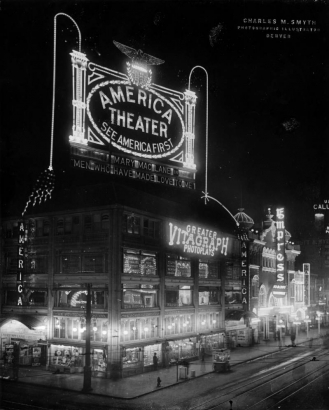 Nighttime view of the America theater at Curtis and 16th (Sixteenth) Streets in Denver, Colorado; shows storefronts, a popcorn cart, and electric signs: "America Theater - Mary Maclane in Men Who Have Made Love To Me," "Greater Vitagraph Photoplays," and "Empress."