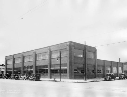 View of the Meade and Mount Construction Company building at 27th (Twenty-seventh) and Larimer Streets in the Five Points neighborhood of Denver, Colorado. Automobiles are parked near the two-story brick warehouse.