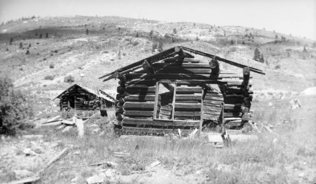 View of dilapidated cabins in Independence (Pitkin County), Colorado; features barren hills with new growth.