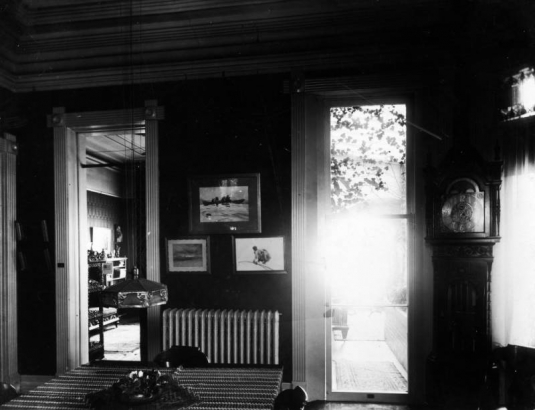 Interior view of the Bancroft house in Denver, Colorado; decor includes a leaded glass lamp, a grandfather clock, and framed art including paintings by Winslow Homer.