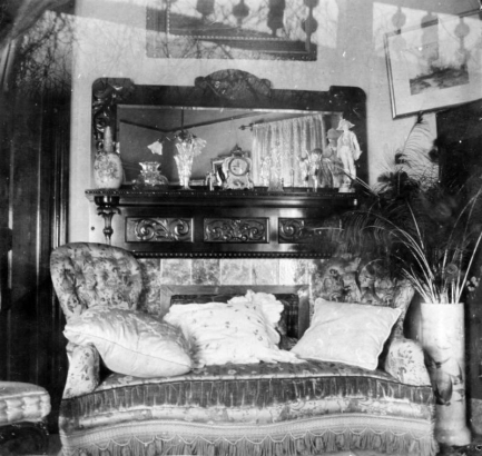 Interior view of the Henry Viley Johnson residence in Denver, Colorado; decor includes a velvet couch with pillows, a mantle with mirror, and vase of peacock feathers.