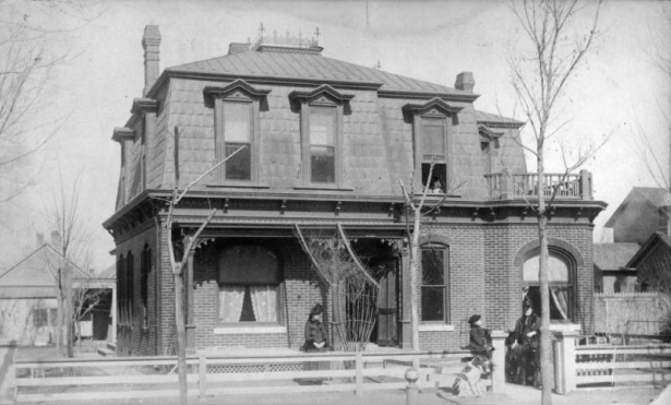 View of the George W. Kramer home at 2445 California Street in the Five Points neighborhood of Denver, Colorado; features a mansard roof, terrace, and covered porch. Women pose with a boy and a dog.