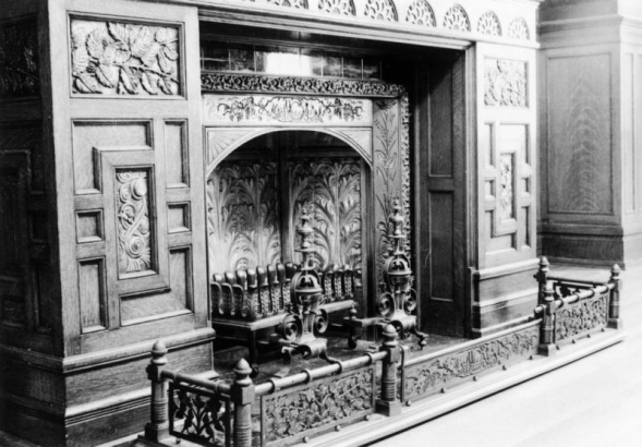 Interior view of a fireplace in the dining room of the David Moffat house at 808 Grant Street in the Capitol Hill neighborhood of Denver, Colorado. A decorative wooden mantle and metal grates are nearby.