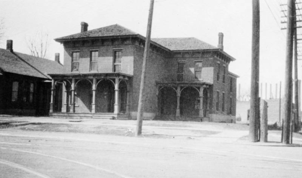 View of the John Kernan Mullen house at Lawrence and 9th (Ninth) Streets in the Auraria neighborhood of Denver, Colorado. The two-story brick house has a hip roof, chimneys, and covered porches.