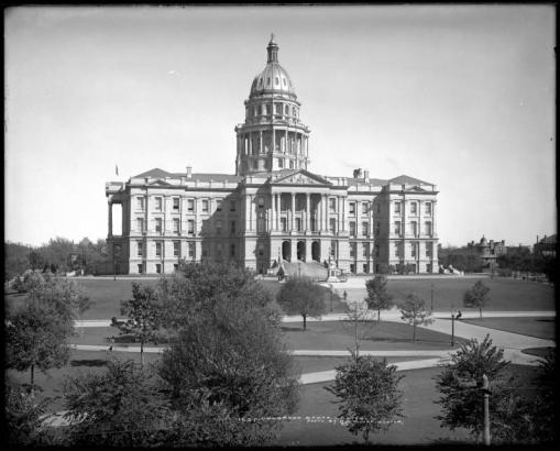 Exterior view of Colorado State Capitol and grounds, Denver, Colorado; Capitol dome with gold-leaf completed in 1908; landscaped grounds, trees, sidewalks; large residence across street from Capitol, center right.
