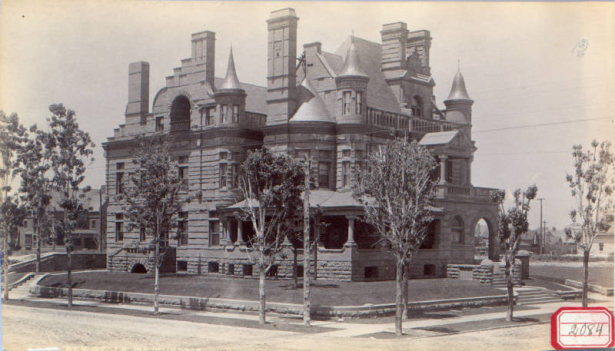 View of John A. McMurtrie home at 1007 Pennsylvania Street, Capitol Hill neighborhood, Denver, Colorado; features rusticated stone, turrets, arches, a covered porch, and ornate chimneys.