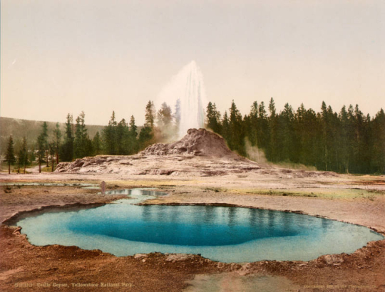View of Castle Geyser in the process of eruption and a hot spring pool in Upper Geyser Basin, Yellowstone National Park, Wyoming.