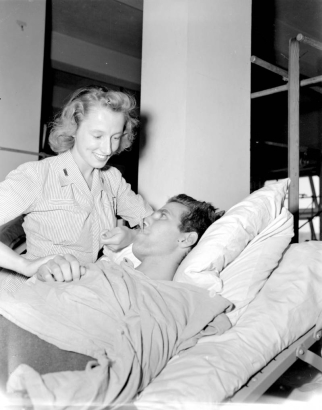A nurse takes the temperature and pulse of Tenth Mountain Division soldier, S/Sergeant George V. Geiss as he lies in his hospital bed in Italy.