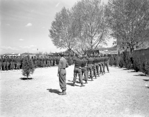 A guard of honor fires volleys during the memorial service for the dead of the Tenth Mountain Division at the American Military Cemetery in Castelfiorentino (Florence Province), Italy. The assembled company stands at attention.