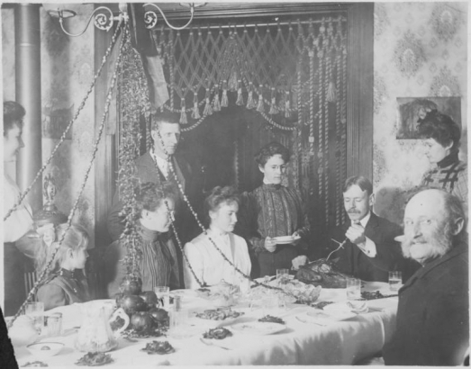 George Leitch prepares to carve a turkey on Thanksgiving in his house at 2957 Humboldt Street in Denver, Colorado. May, men, women, and a girl look on.