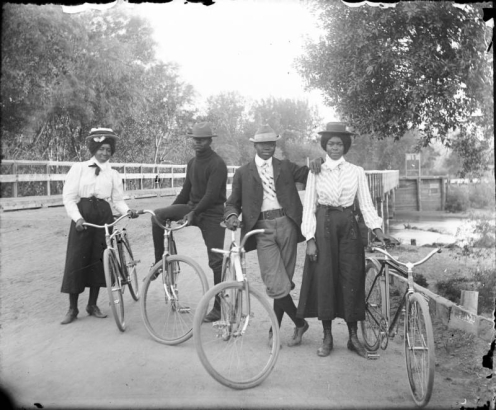 Outdoor portrait of well dressed Black men and women with bicycles on the Alameda Avenue bridge, in Denver, Colorado.