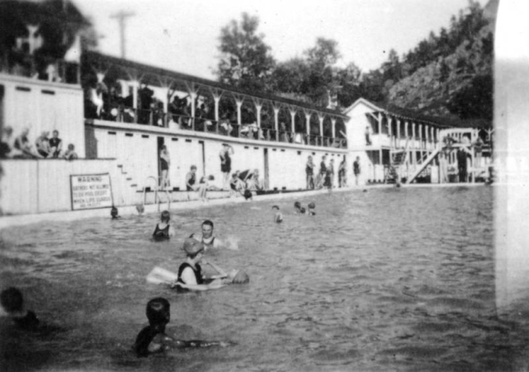 Swimmers and onlookers are at the pool in Eldorado Springs, Colorado. A sign near the pool reads: "Warning Bathers Are Not Allowed To Use Pool Except When Life Guards Are On Duty."