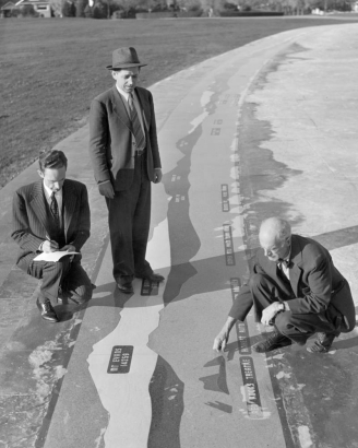 Men examine a panoramic mountain index at Cranmer Park in the Hilltop Neighborhood of Denver, Colorado; mountain names and elevations are rendered in stone tile.