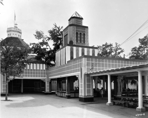 View of buildings at Elitch's Gardens in Denver, Colorado; tables and benches are under a shelter, and painted designs cover the walls.
