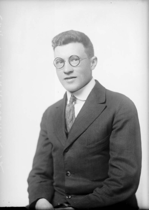 Studio portrait of E. M. Winterbourne. He wears glasses, a suit, and tie.