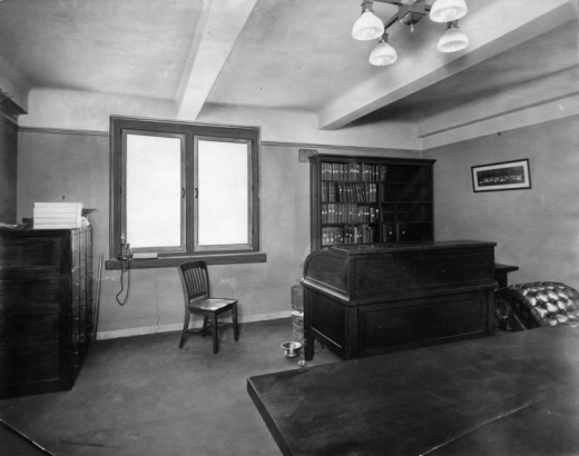 Interior view of a librarian's office in the Denver Public Library at Colfax Avenue and Bannock Street in the Civic Center neighborhood of Denver, Colorado. A desk, chair, file cabinets, telephone, and bookcase are in the room.