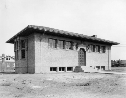 View of the Park Hill Branch of the Denver Public Library at Dexter Street and Montview Boulevard in Denver, Colorado; features a tile roof, stucco finish, leaded glass, and a bay window with entablature.