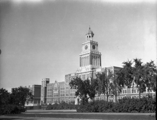 View of East High School in the City Park neighborhood of Denver, Colorado; features stone trim, a clock tower, and a belfry.